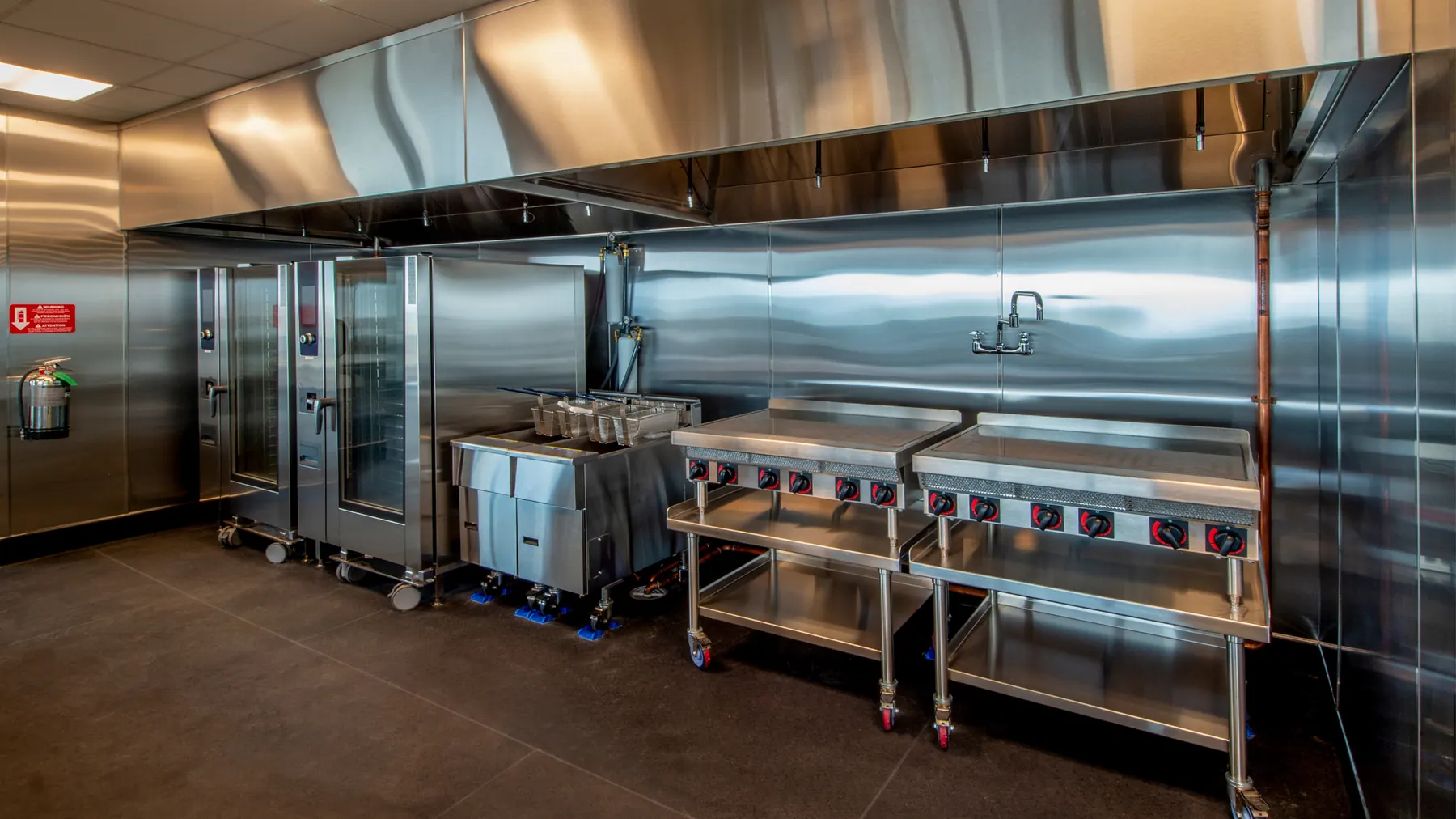 Cocina industrial con hornos combinados, freidora y estufas
